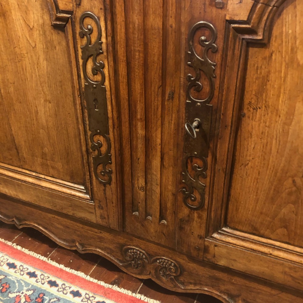 An 18th-century French provincial walnut buffet cabinet featuring a wide top drawer over two carved panelled doors with iron escutcheons and a shaped apron. View V