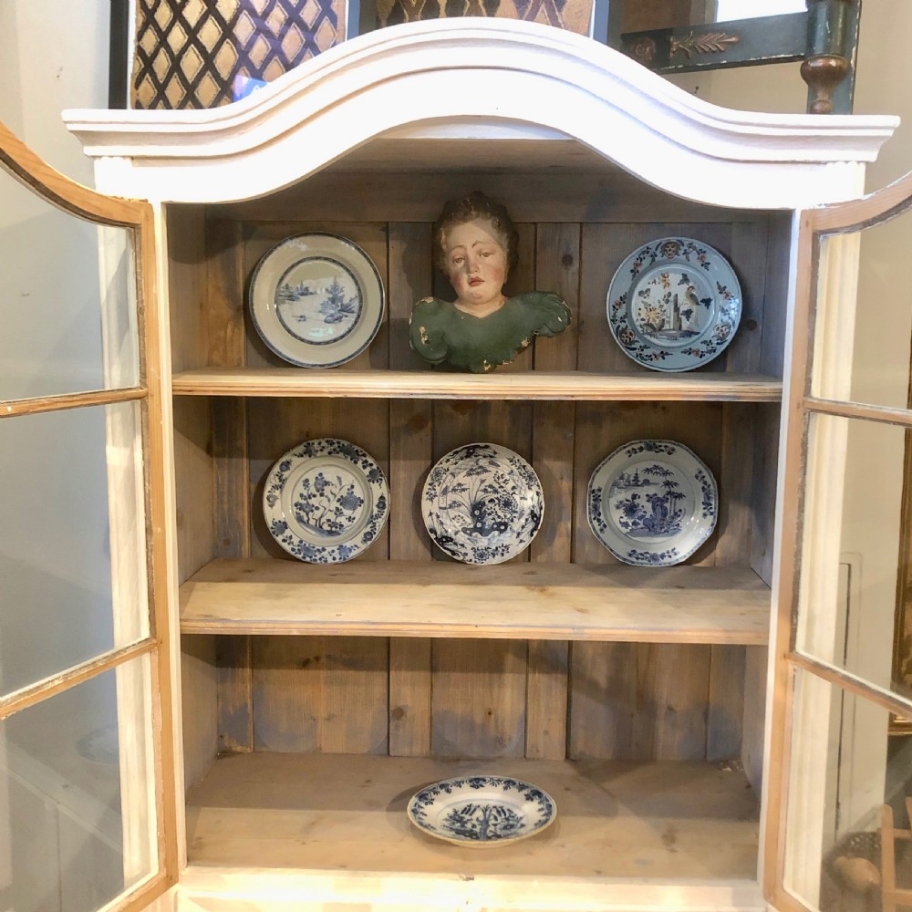 An off-white painted 19th-century French display cabinet featuring arched glazed upper doors, panelled lower cupboard doors, and turned feet. View II