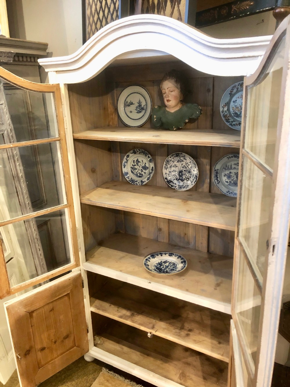 An off-white painted 19th-century French display cabinet featuring arched glazed upper doors, panelled lower cupboard doors, and turned feet. View IV