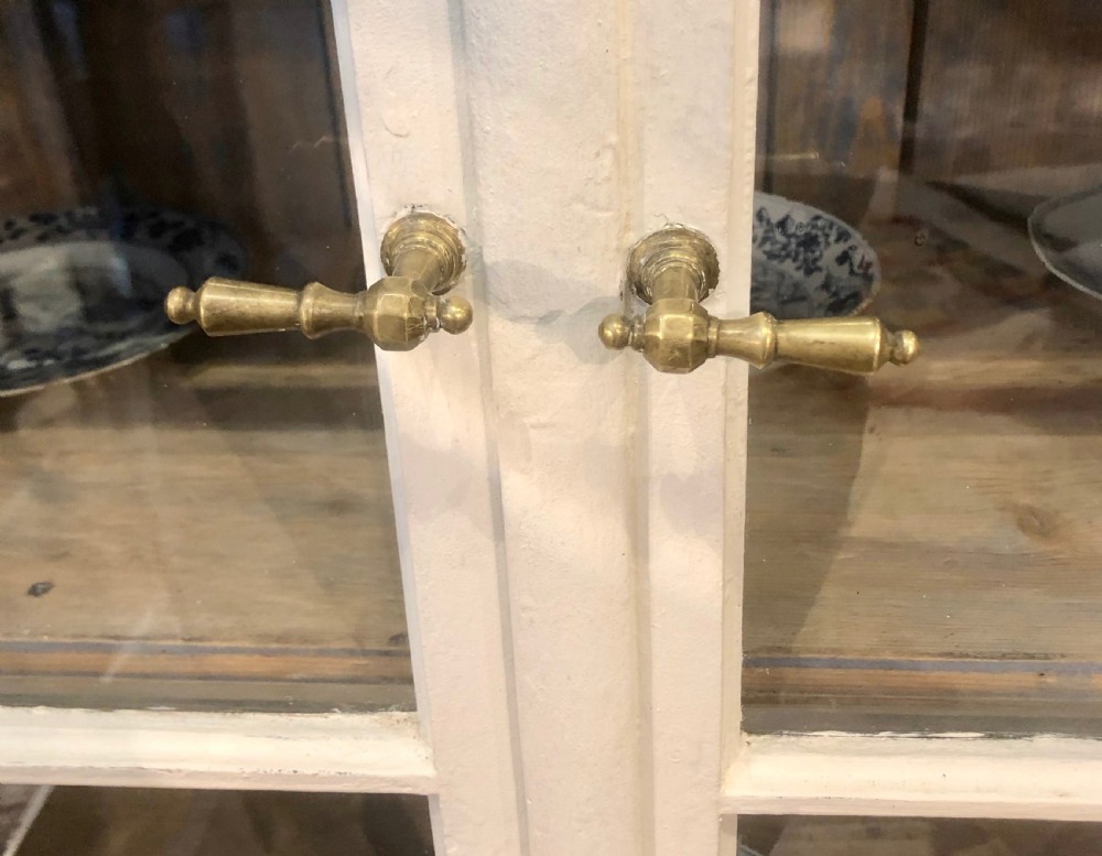 An off-white painted 19th-century French display cabinet featuring arched glazed upper doors, panelled lower cupboard doors, and turned feet. View V