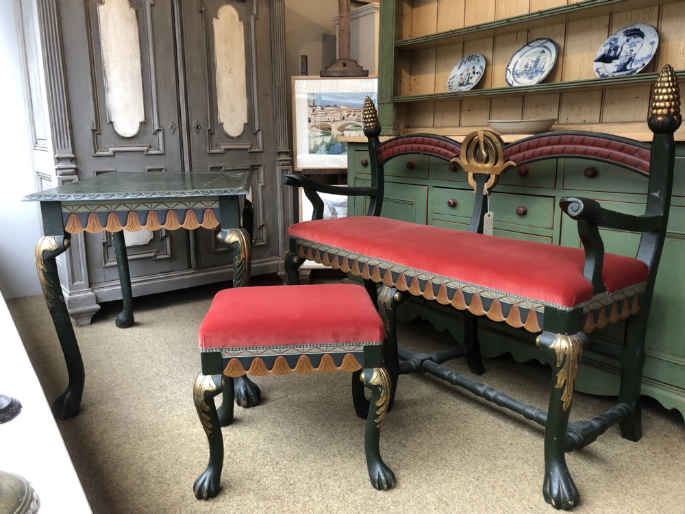 A three-piece Swedish furniture suite featuring a dark green and gilded bench, table, and footstool upholstered in red velvet.