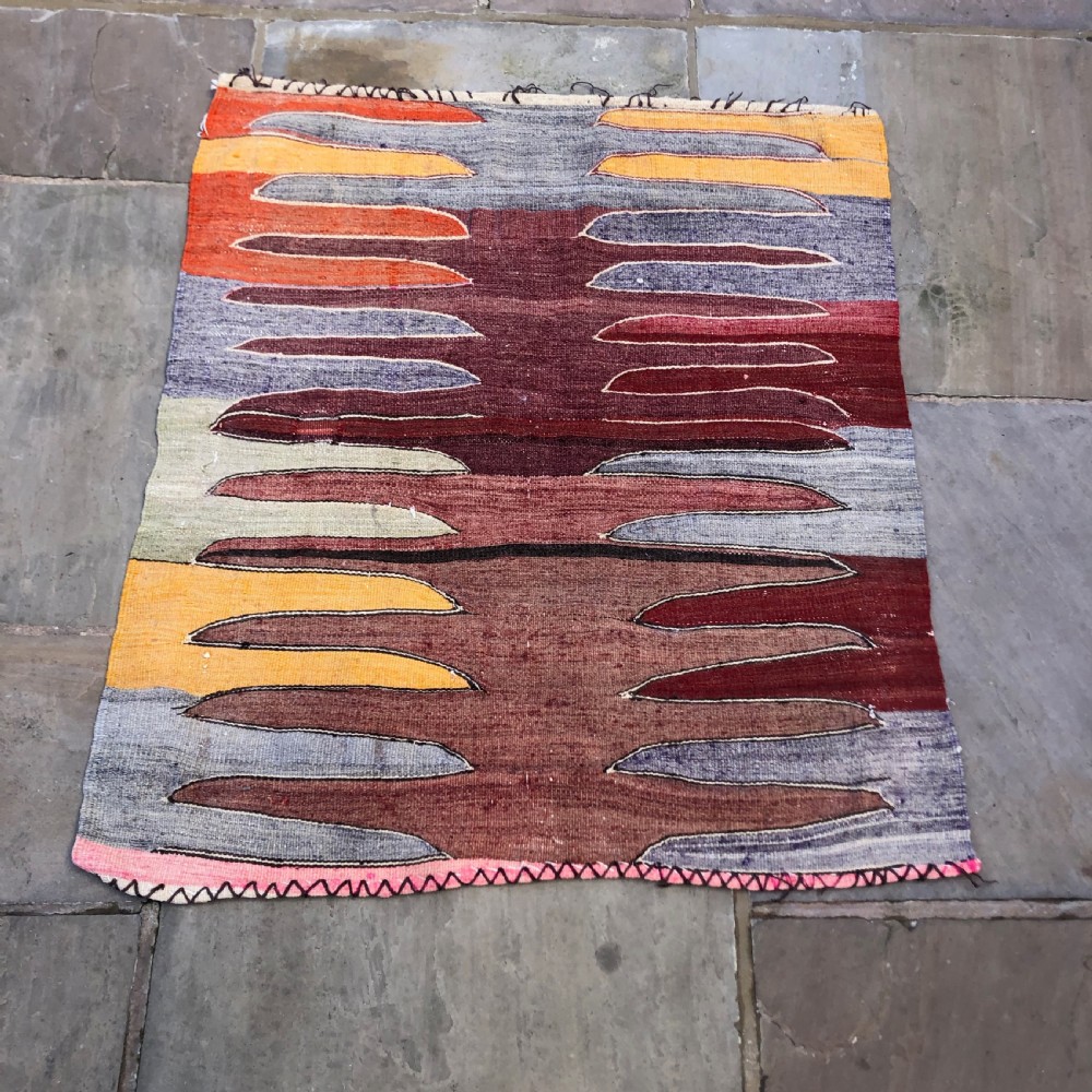 A flatwoven Turkish Afyon kelim rug featuring a central finger motif in shades of terracotta, maroon, grey, orange, and yellow.