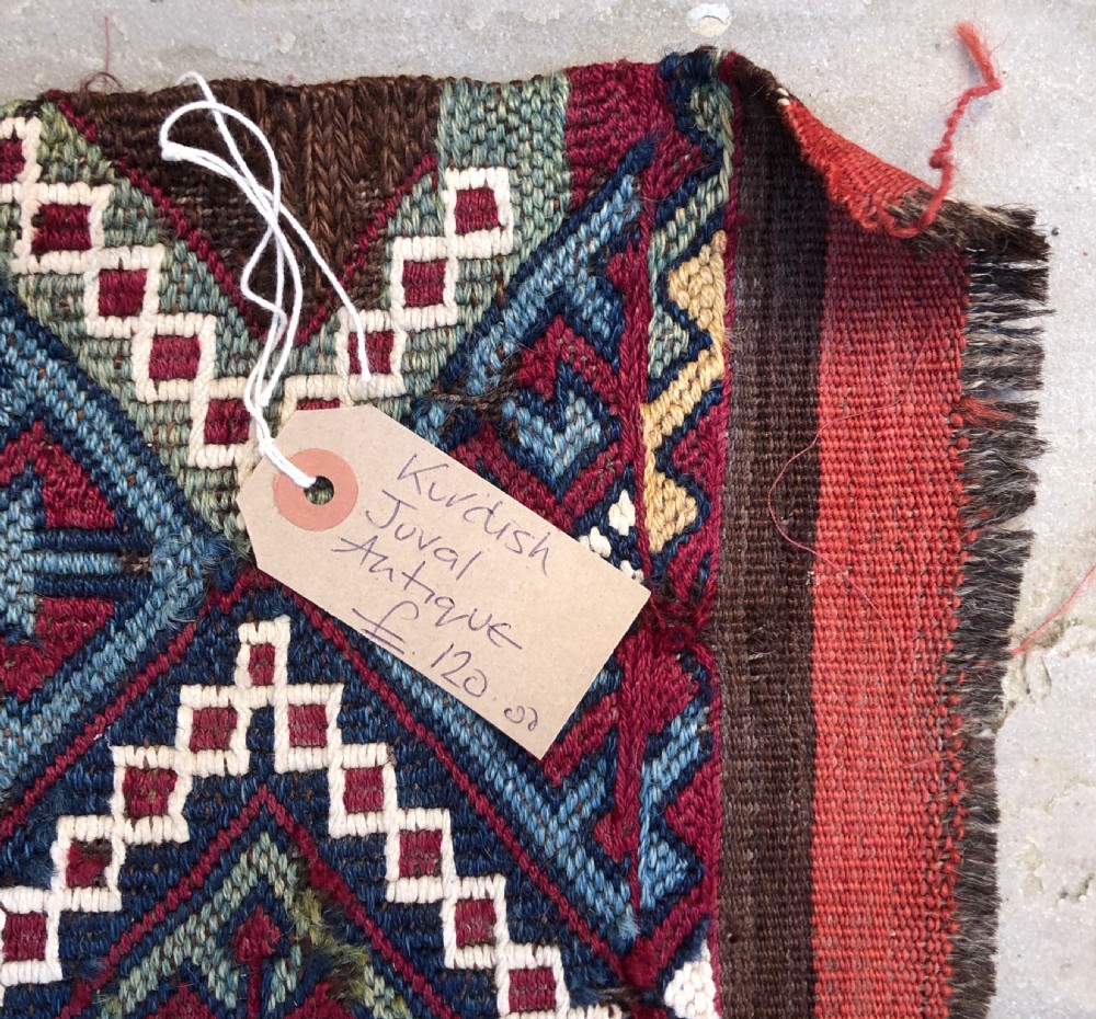 An elongated flat-woven wool textile panel featuring geometric diamond motifs in terracotta red, navy blue, green, mustard yellow, and off-white. View IV