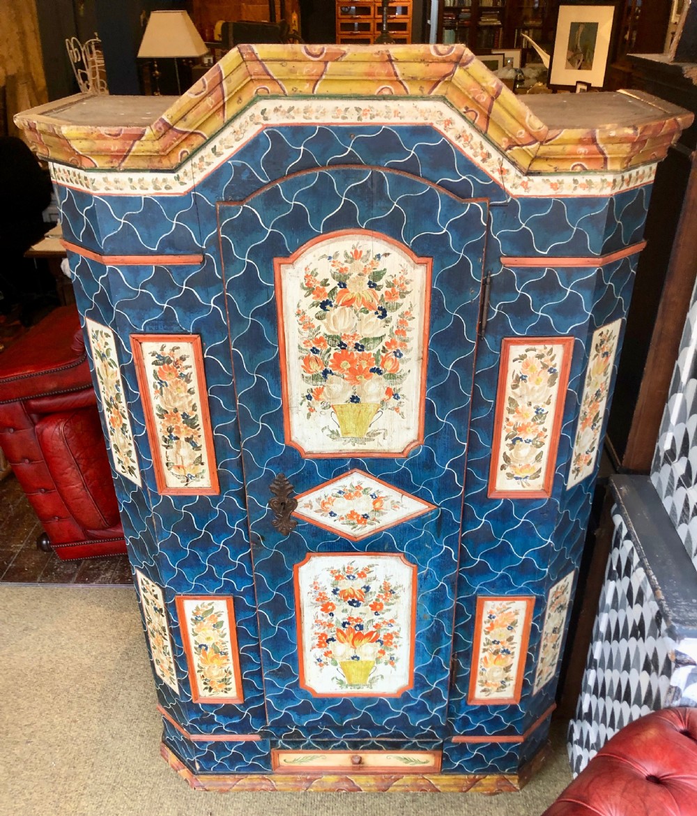 An Austro-Hungarian painted pine marriage armoire featuring a blue ground with geometric lattice motifs, hand-painted floral panels, and a shaped top cornice. View II