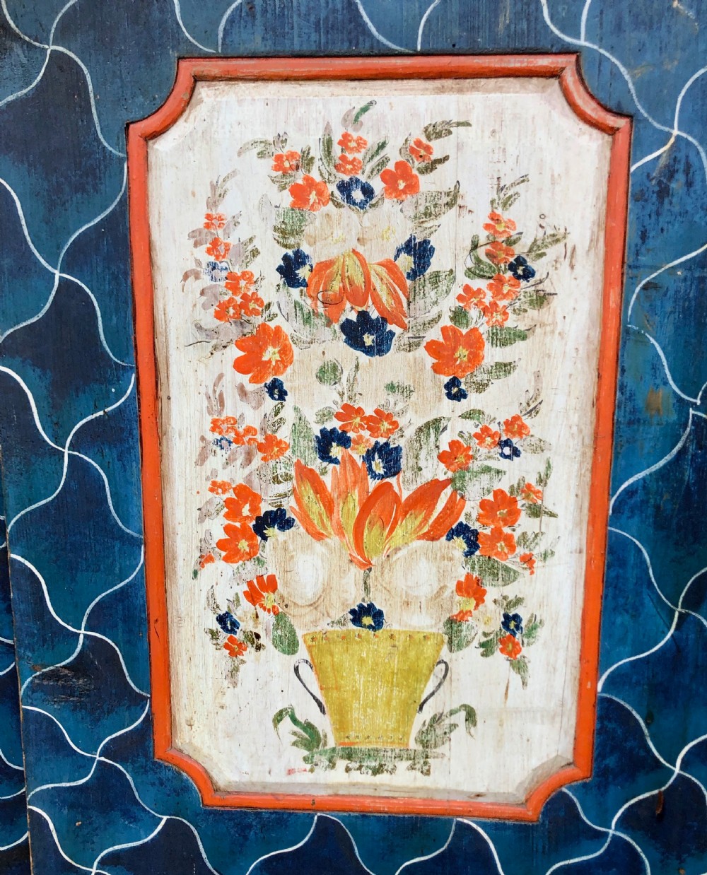 An Austro-Hungarian painted pine marriage armoire featuring a blue ground with geometric lattice motifs, hand-painted floral panels, and a shaped top cornice. View V