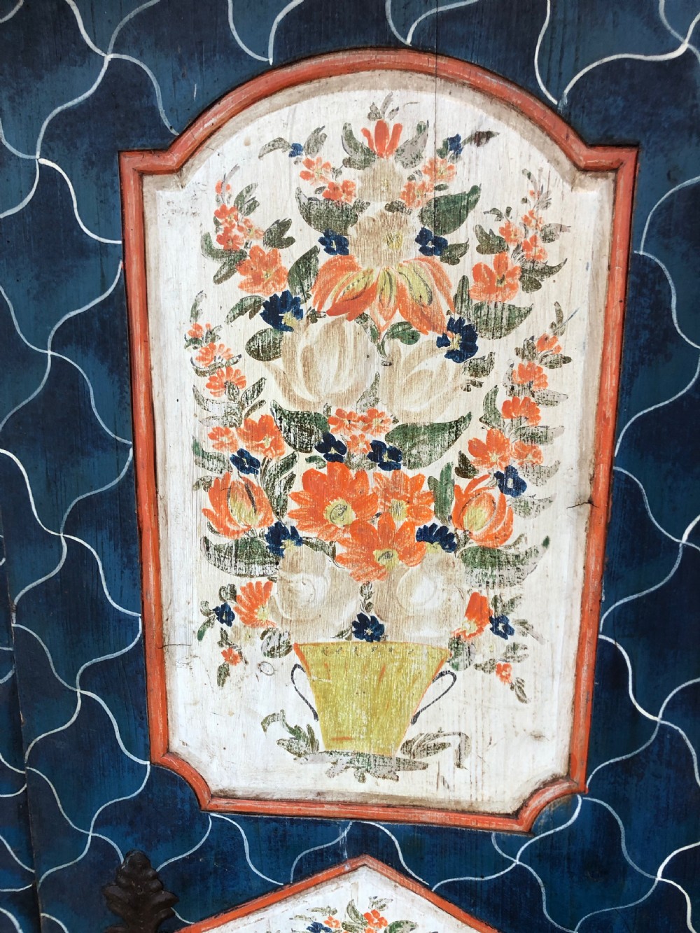 An Austro-Hungarian painted pine marriage armoire featuring a blue ground with geometric lattice motifs, hand-painted floral panels, and a shaped top cornice. View VI
