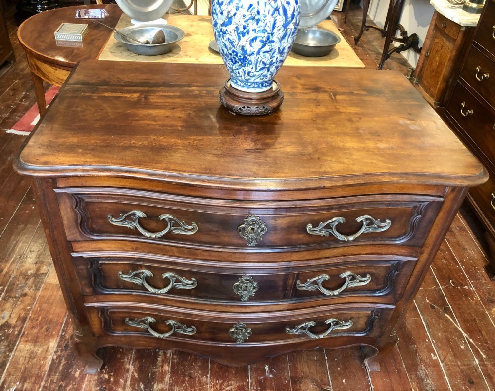 An 18th-century French walnut commode featuring a serpentine front, three drawers with carved moulded frames, cast brass handles, and cabriole legs. View II