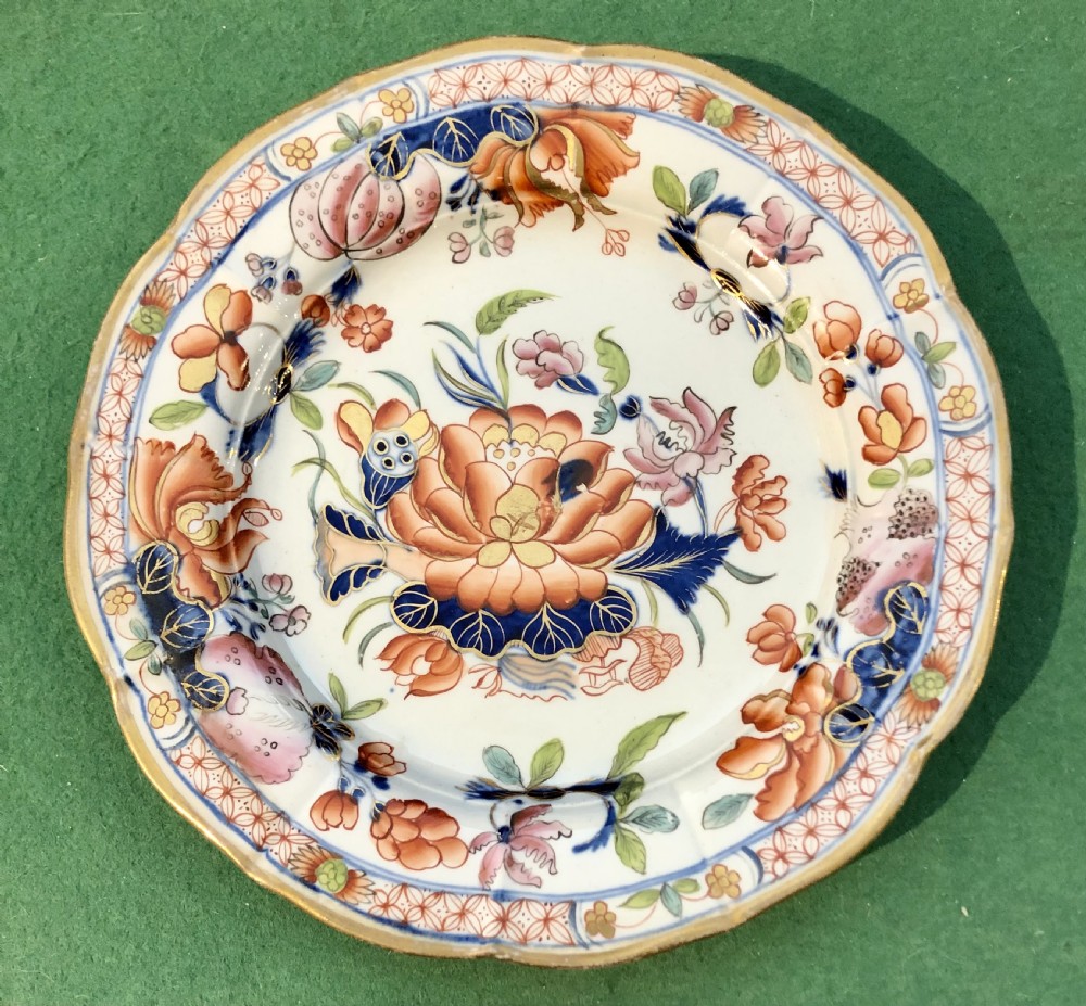 An antique Masons Patent Ironstone plate featuring hand-painted floral motifs in iron red and cobalt blue with a scalloped gilded rim.
