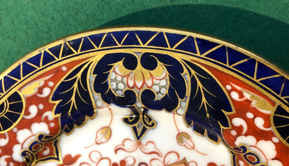 An antique circular porcelain dessert plate decorated with a Japanese-inspired Imari pattern in cobalt blue, terracotta red, and hand-gilded detail. View III