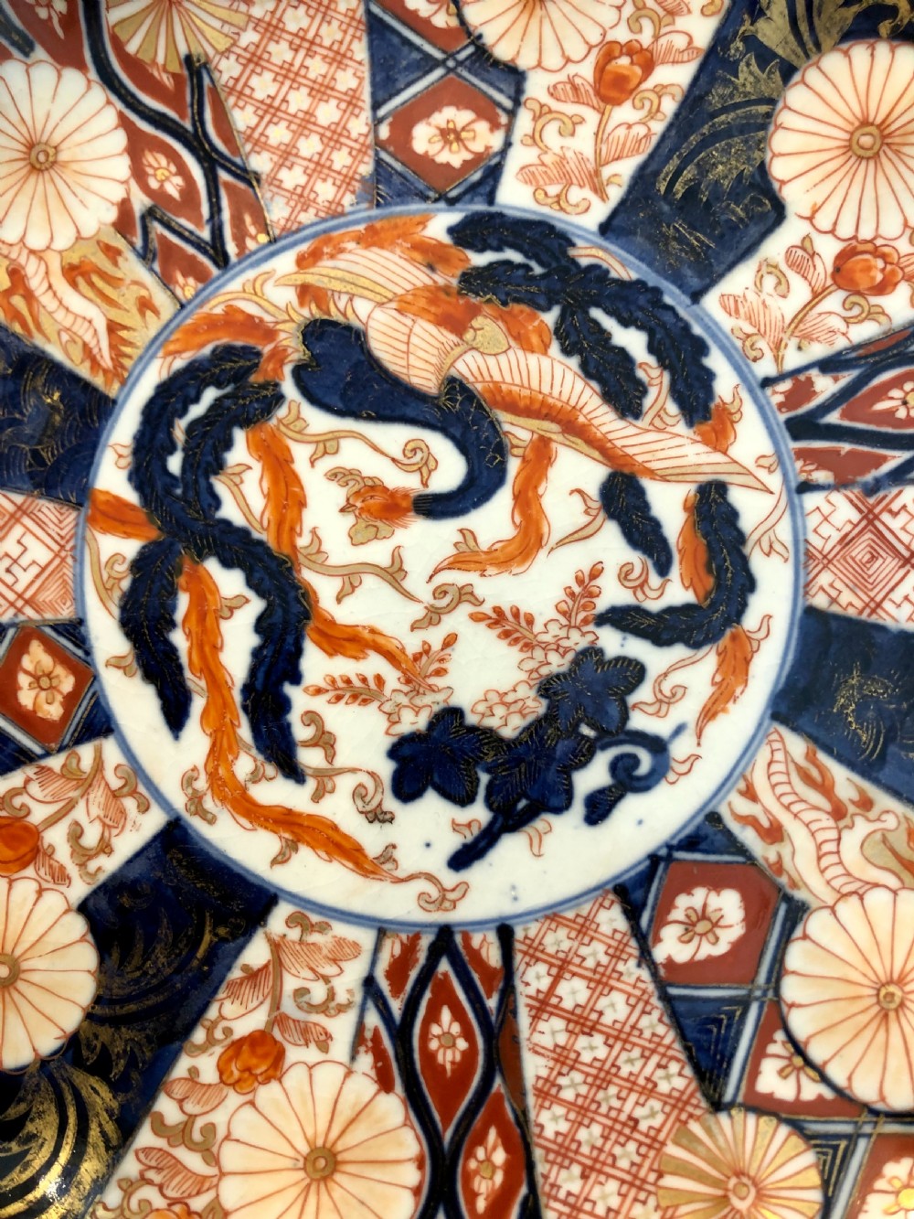 An eighteenth-century Japanese Imari porcelain plate featuring a scalloped edge, central phoenix motif, and alternating panels of cobalt blue, iron-red, and gold leaf floral patterns. View II