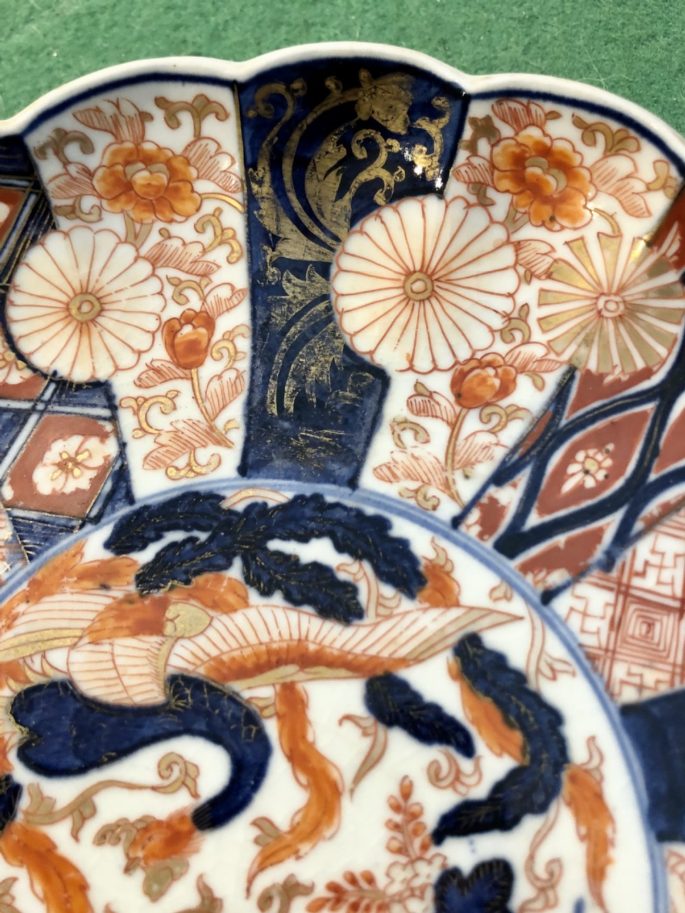 An eighteenth-century Japanese Imari porcelain plate featuring a scalloped edge, central phoenix motif, and alternating panels of cobalt blue, iron-red, and gold leaf floral patterns. View III