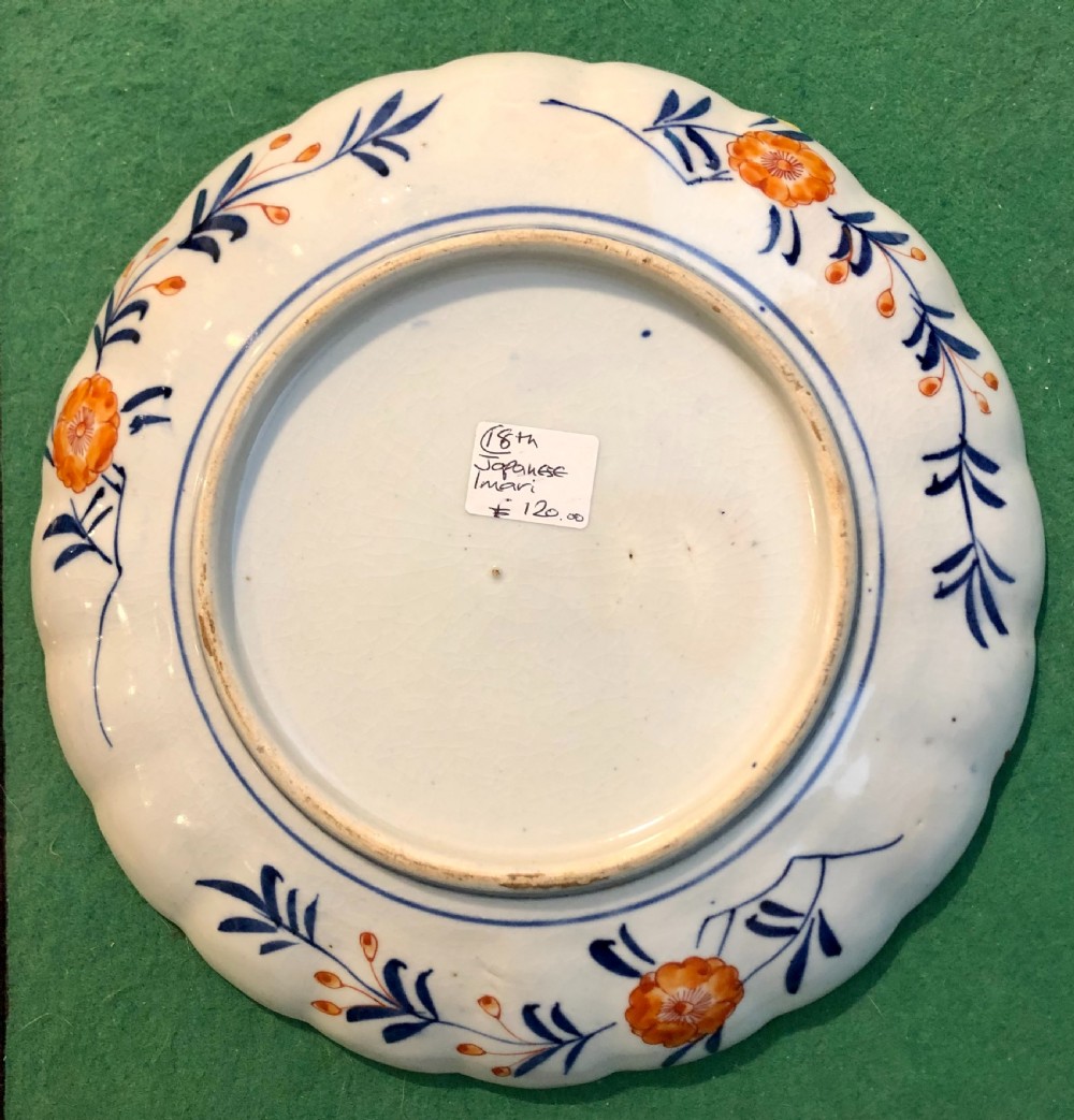 An eighteenth-century Japanese Imari porcelain plate featuring a scalloped edge, central phoenix motif, and alternating panels of cobalt blue, iron-red, and gold leaf floral patterns. View IV