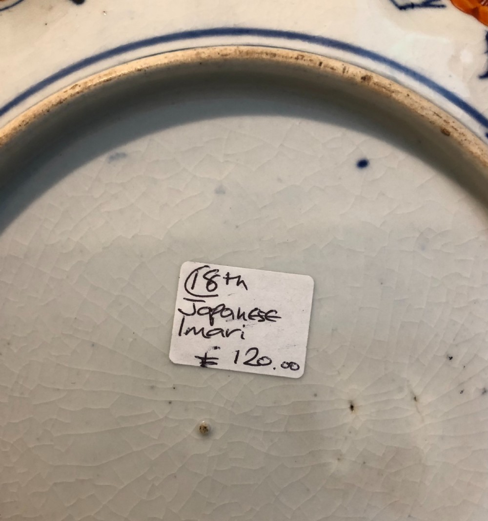 An eighteenth-century Japanese Imari porcelain plate featuring a scalloped edge, central phoenix motif, and alternating panels of cobalt blue, iron-red, and gold leaf floral patterns. View V