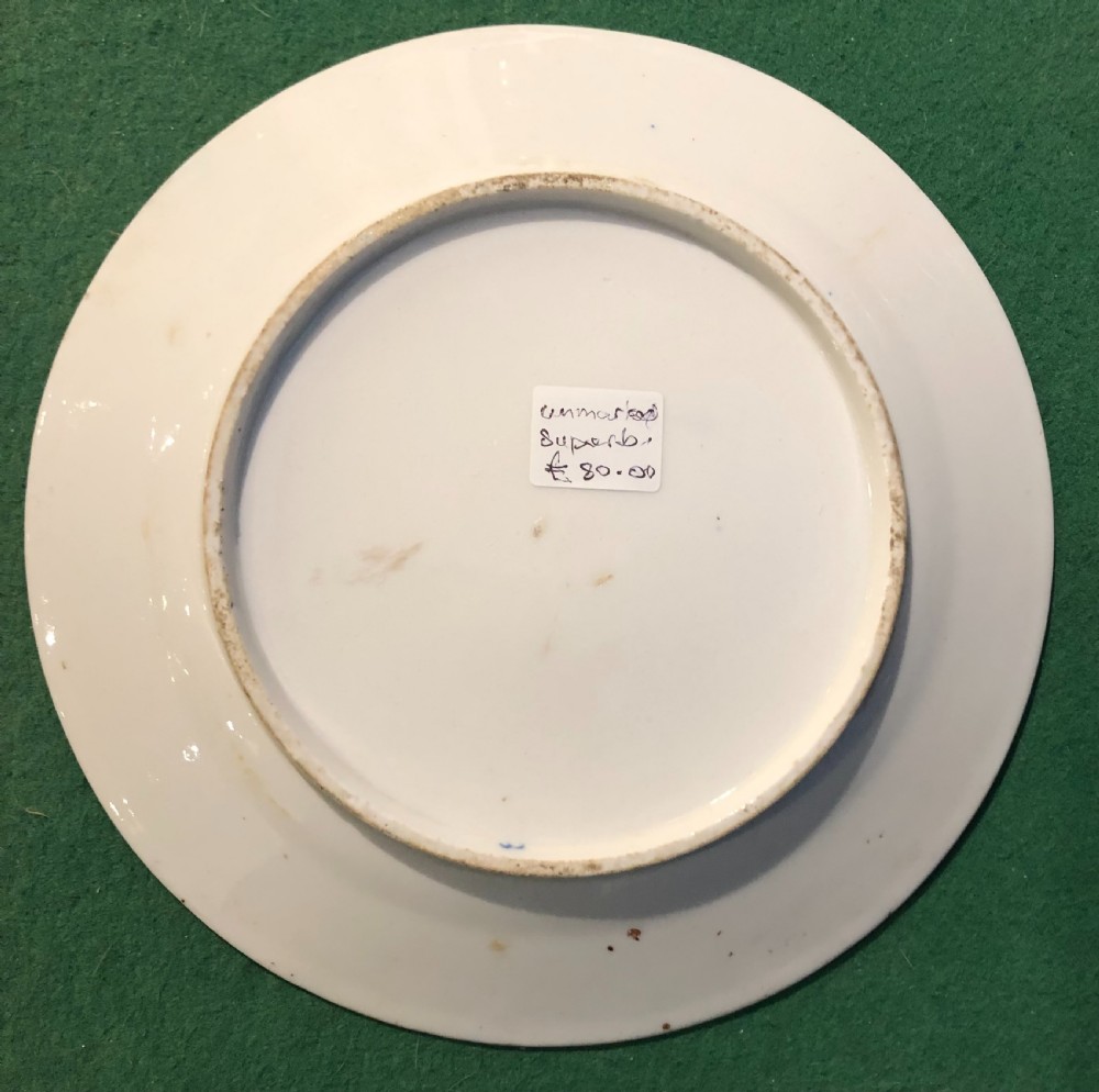 A circular 19th-century Imari style porcelain dessert plate decorated with cobalt blue scrolls, iron red blossoms, green leaves, and gilded accents on a white ground. View V