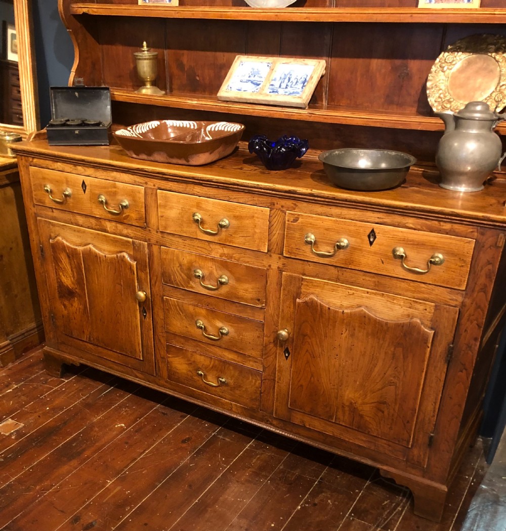 An 18th-century English elm dresser with a three-shelf plate rack, lower drawers with brass handles, and two panelled cupboard doors. View II