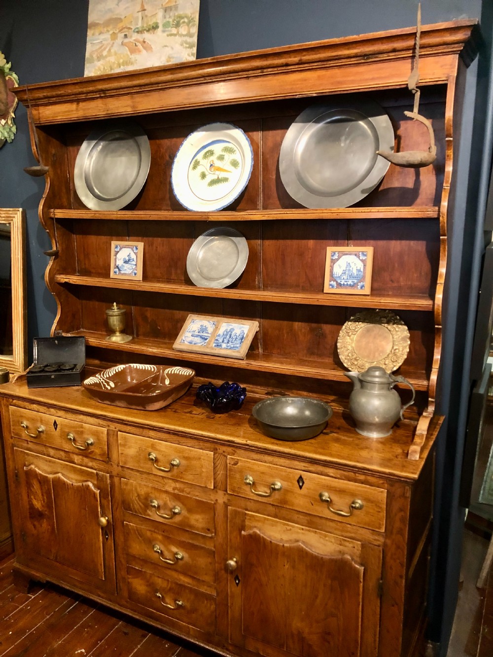An 18th-century English elm dresser with a three-shelf plate rack, lower drawers with brass handles, and two panelled cupboard doors. View III