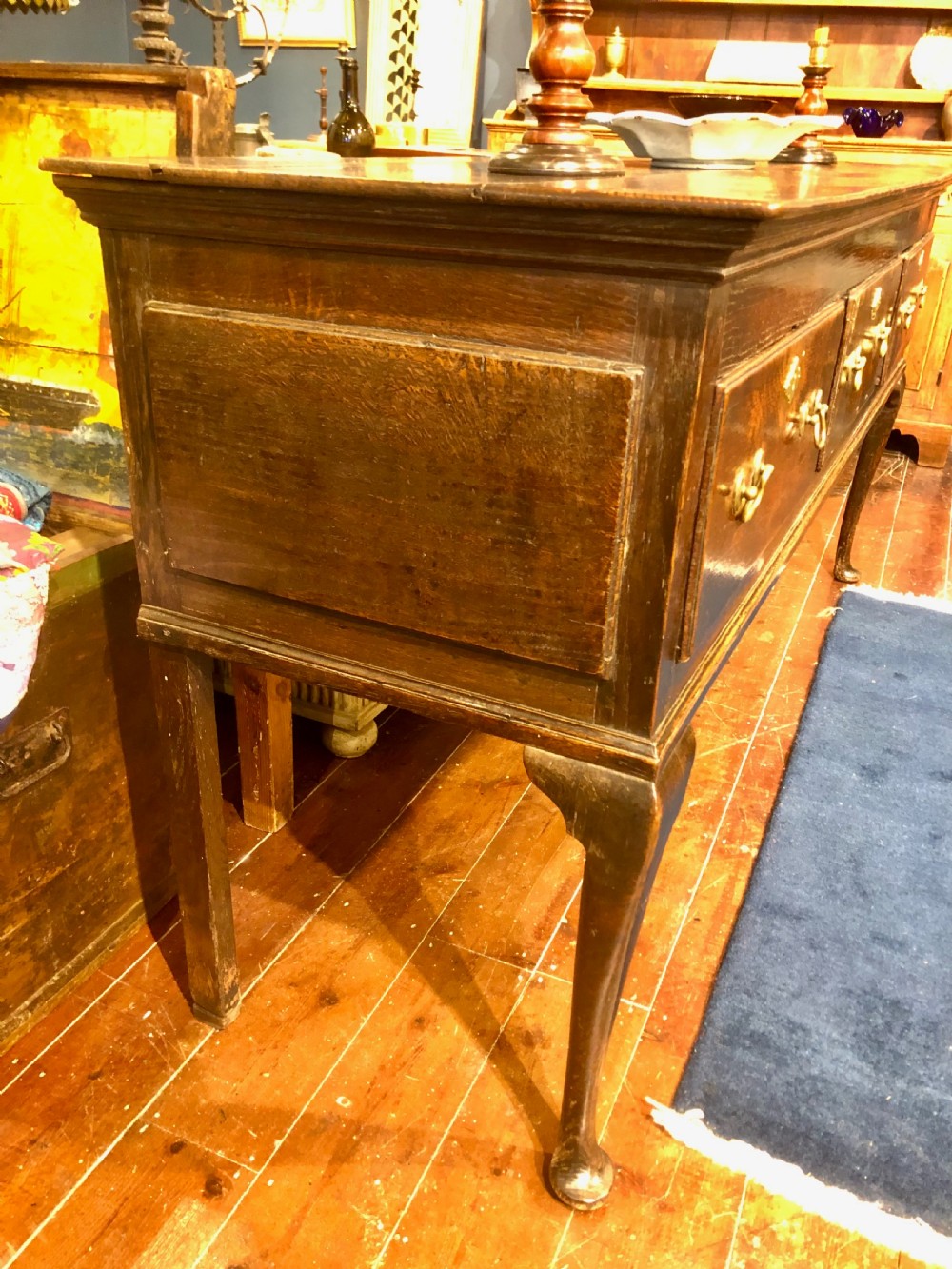 An 18th-century dark oak dresser base featuring three brass-handled drawers supported on slender cabriole legs. View III