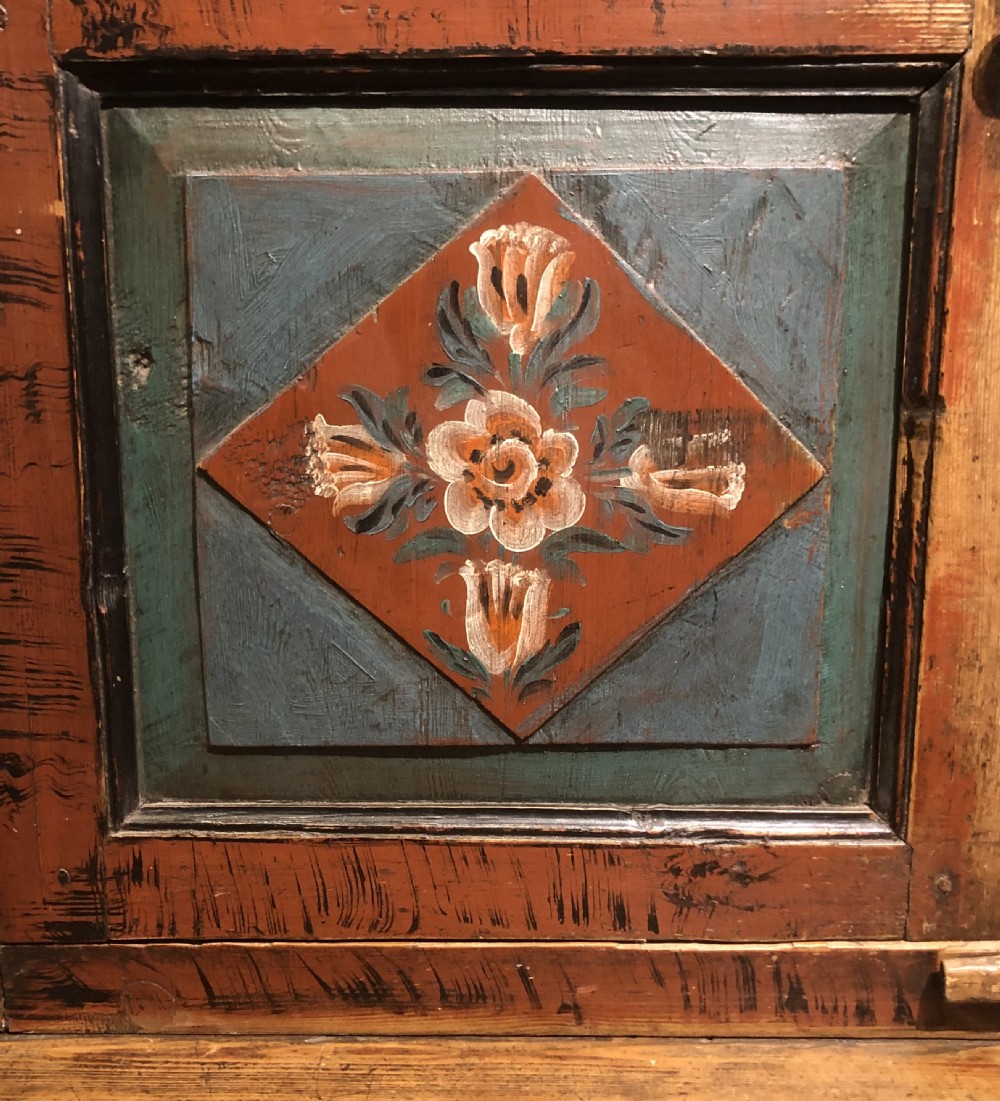A 19th-century Austro-Hungarian two-tier wooden cupboard decorated with hand-painted floral panels in terracotta red, cream, and teal blue tones. View V