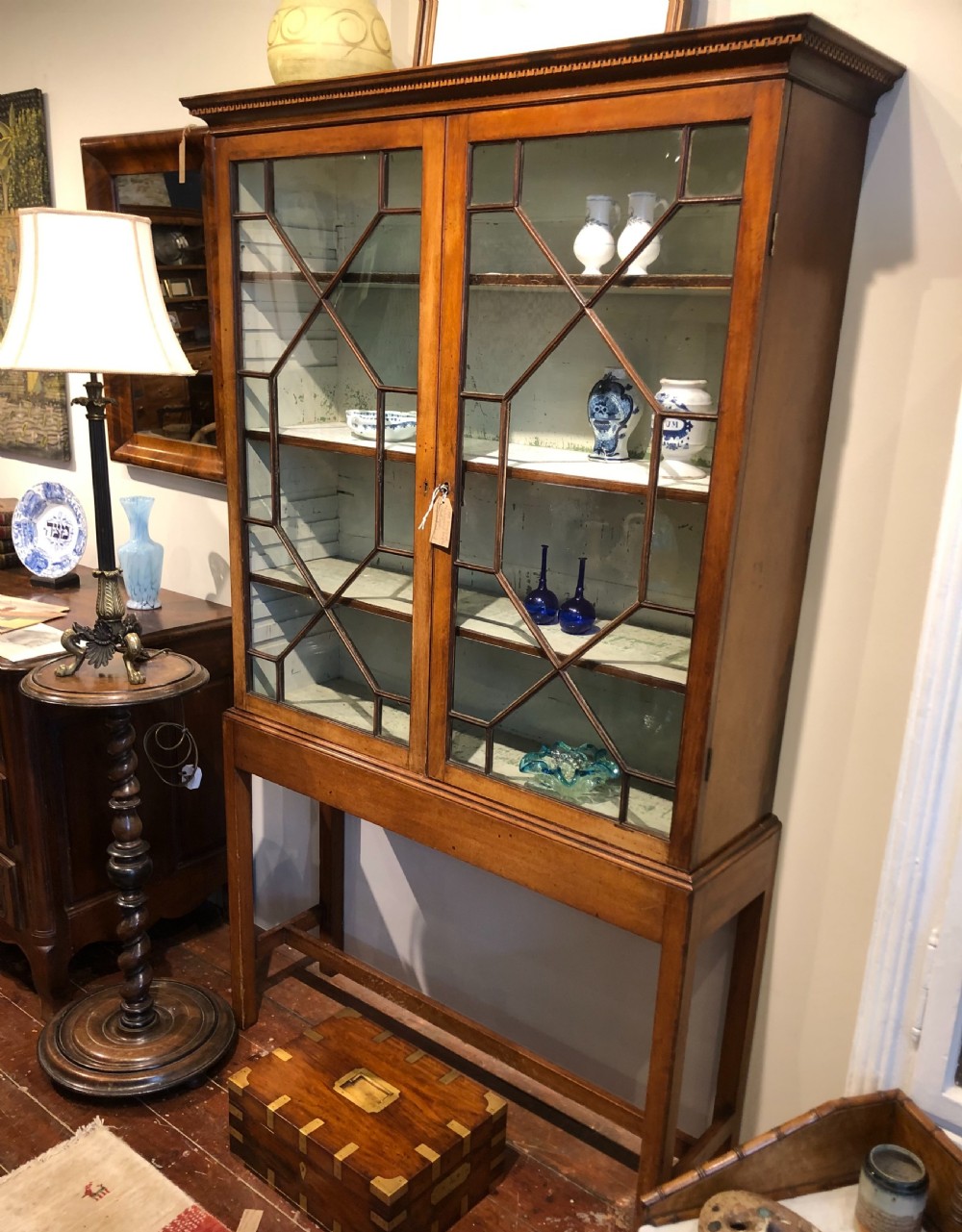 A Georgian mahogany glazed display cabinet on a tall stand with geometric astragal glazing bars and a light-painted interior. View III