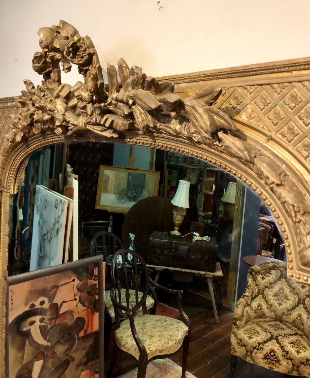 A large rectangular French giltwood wall mirror featuring an arched inner frame with floral cresting and carved decorative borders. View III