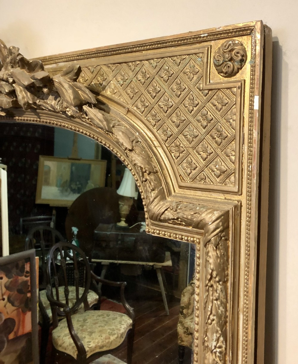 A large rectangular French giltwood wall mirror featuring an arched inner frame with floral cresting and carved decorative borders. View IV