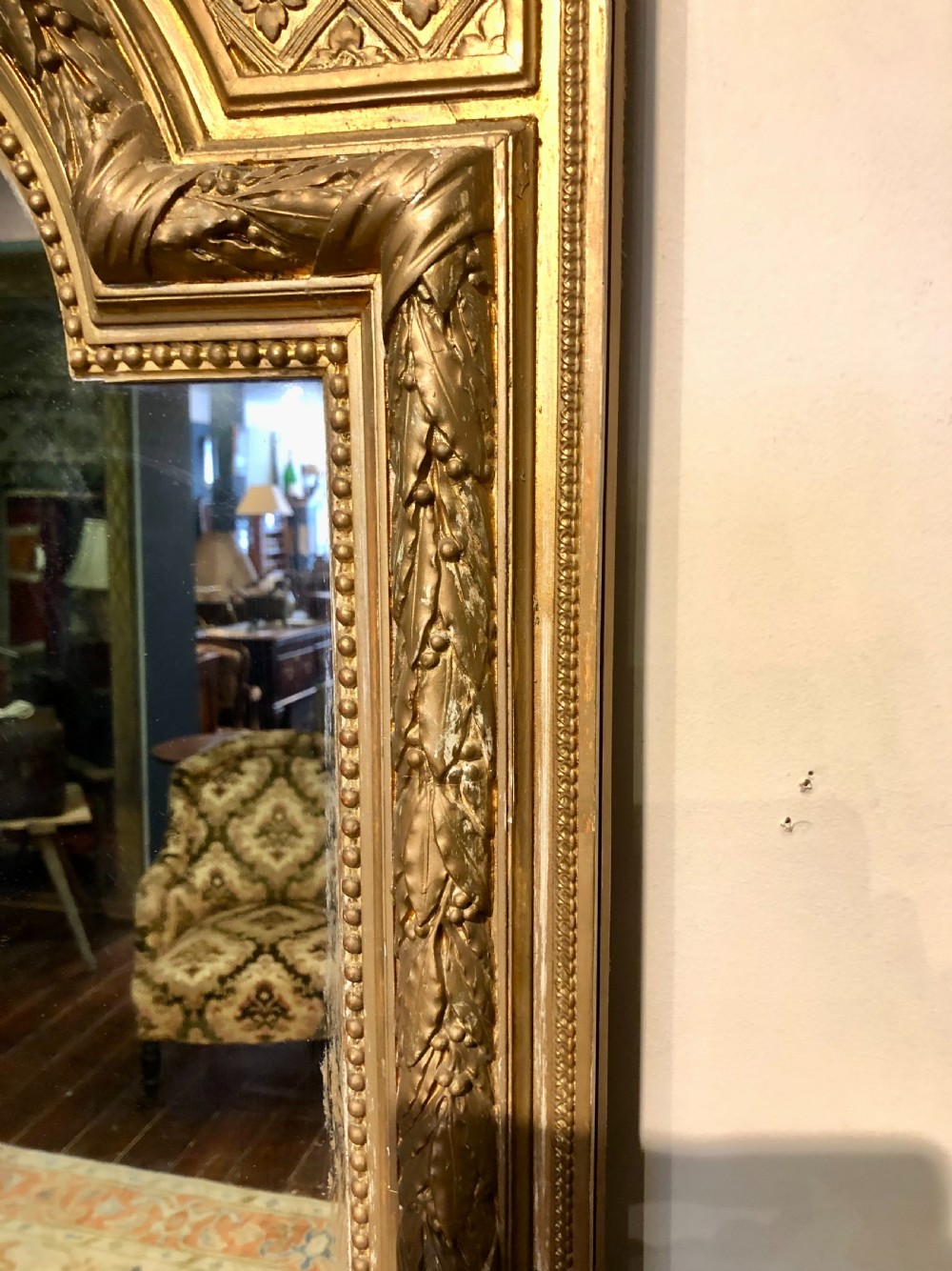 A large rectangular French giltwood wall mirror featuring an arched inner frame with floral cresting and carved decorative borders. View VII