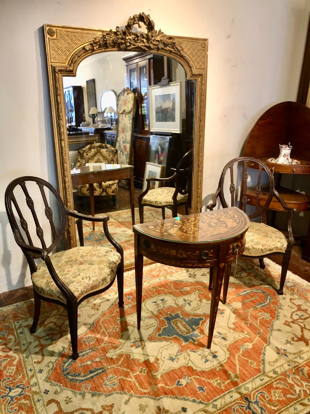 A large rectangular French giltwood wall mirror featuring an arched inner frame with floral cresting and carved decorative borders. View VIII