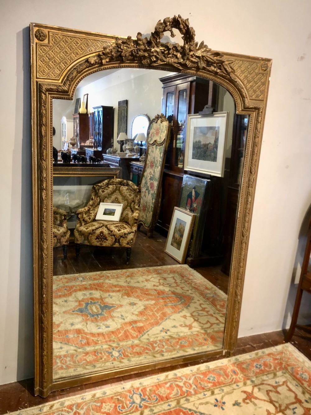 A large rectangular French giltwood wall mirror featuring an arched inner frame with floral cresting and carved decorative borders. View IX