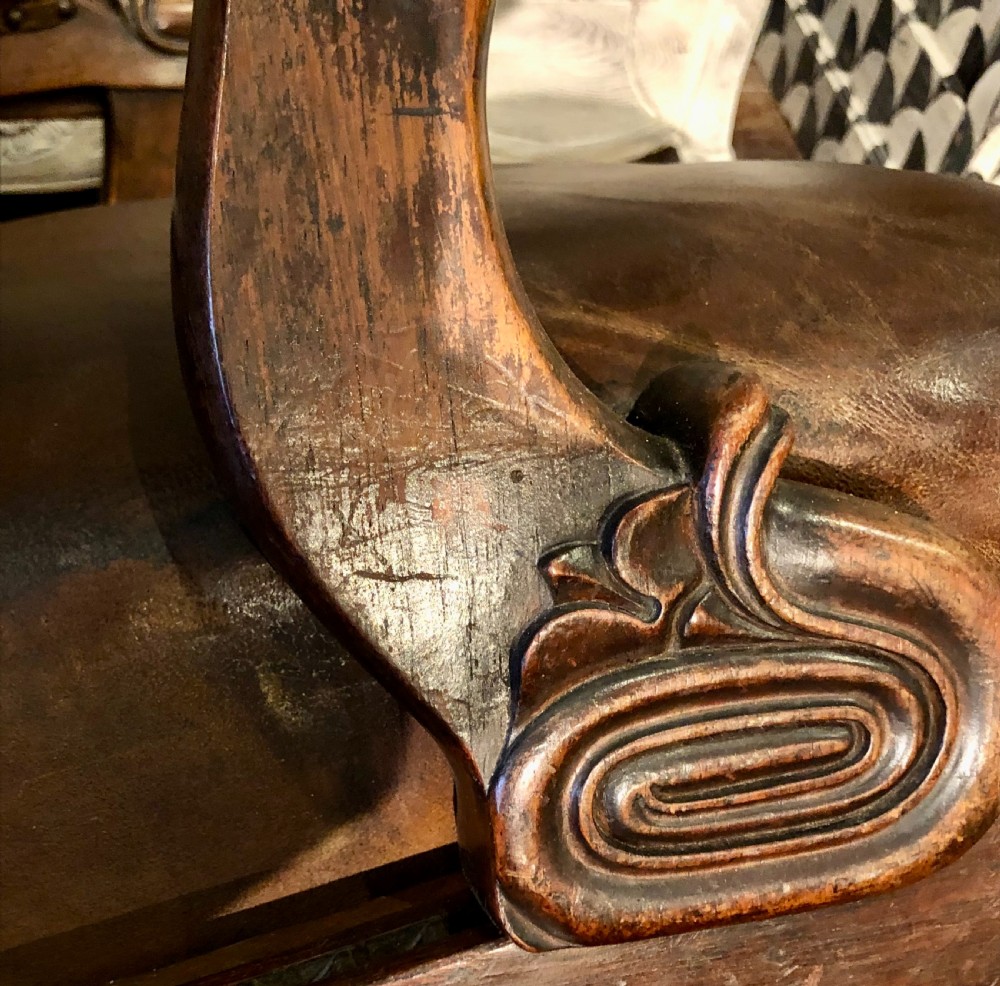 A Regency mahogany library armchair upholstered in warm brown leather with scroll arms, reeded front legs, brass castors, and studding. View VII