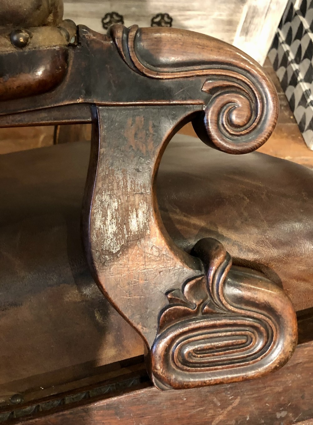A Regency mahogany library armchair upholstered in warm brown leather with scroll arms, reeded front legs, brass castors, and studding. View VIII
