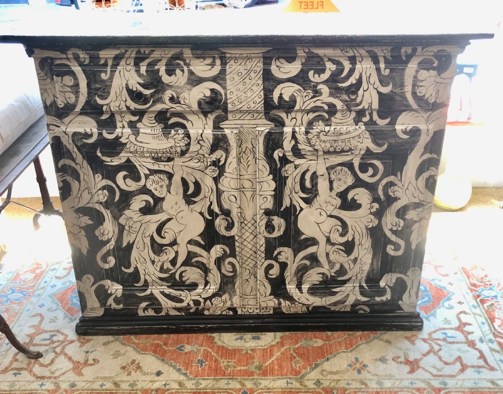A two-door wooden French buffet cabinet hand-painted with black and white grotesque foliate scrollwork and human figures.