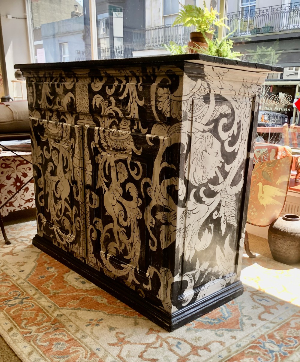 A two-door wooden French buffet cabinet hand-painted with black and white grotesque foliate scrollwork and human figures. View III