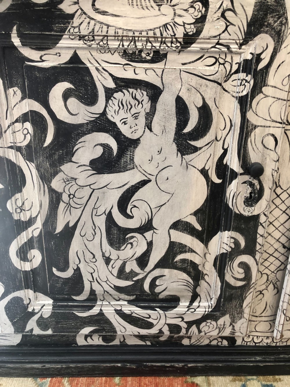 A two-door wooden French buffet cabinet hand-painted with black and white grotesque foliate scrollwork and human figures. View VII