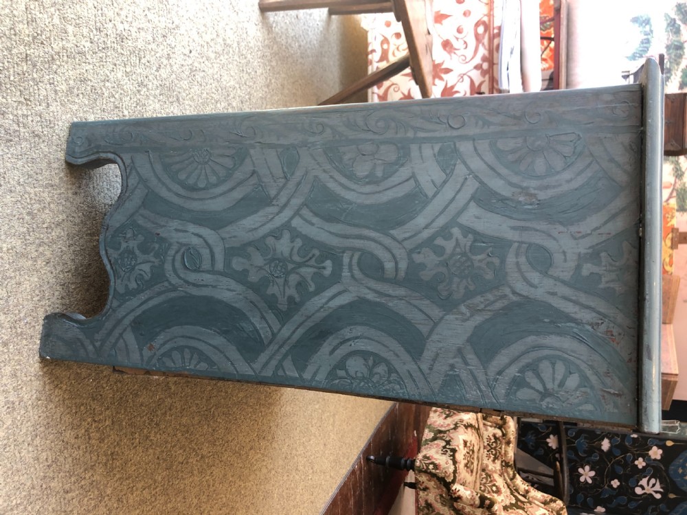A small wooden cupboard hand-painted in muted sage green with light grey strapwork and floral motifs, featuring a single top drawer and two panelled doors. View VI