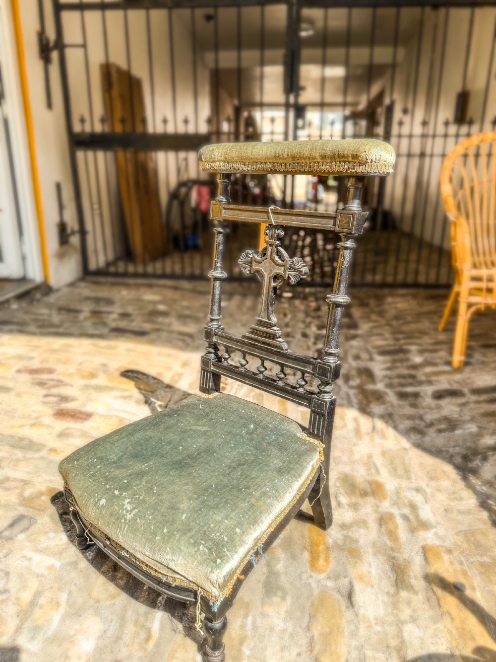 A 19th-century ebonised wood prie-dieu prayer chair featuring a carved central cross, turned upright spindles, and sage green velvet upholstery on the kneeling seat and top rail. View II