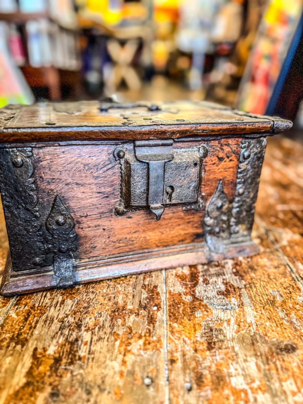 A 17th-century rectangular wooden box featuring heavy wrought-iron corner braces, decorative straps, a top carrying handle, and an oversized front lockplate. View II