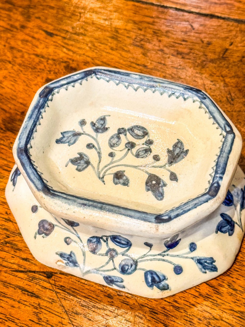 An eighteenth-century octagonal English Delftware salt cellar crafted from tin-glazed earthenware and decorated with hand-painted cobalt blue botanical patterns.