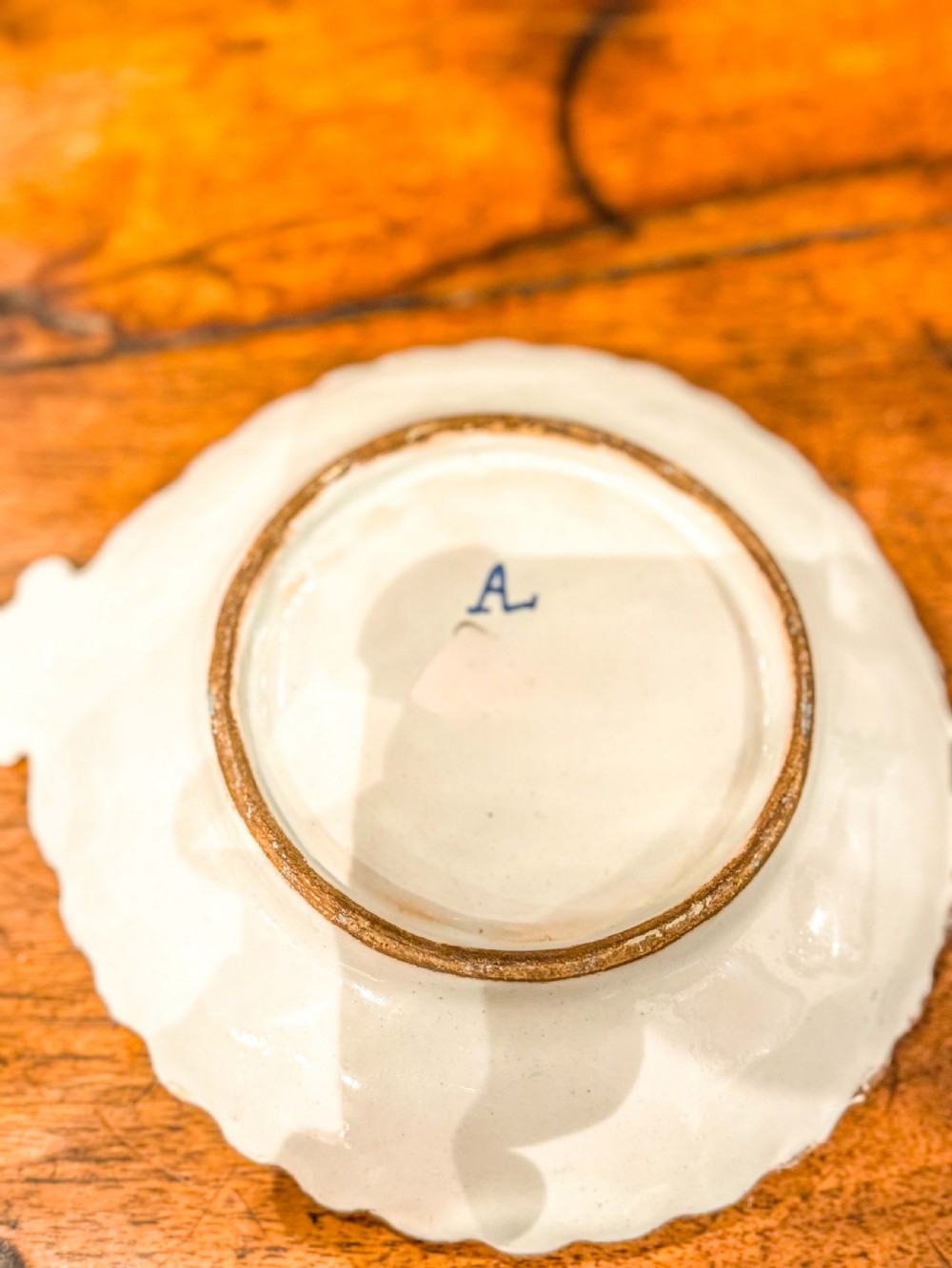 A nineteenth-century French blue and white faience shell-shaped vide-poche dish decorated with a central figure, floral sprigs, and a scalloped rim. View II