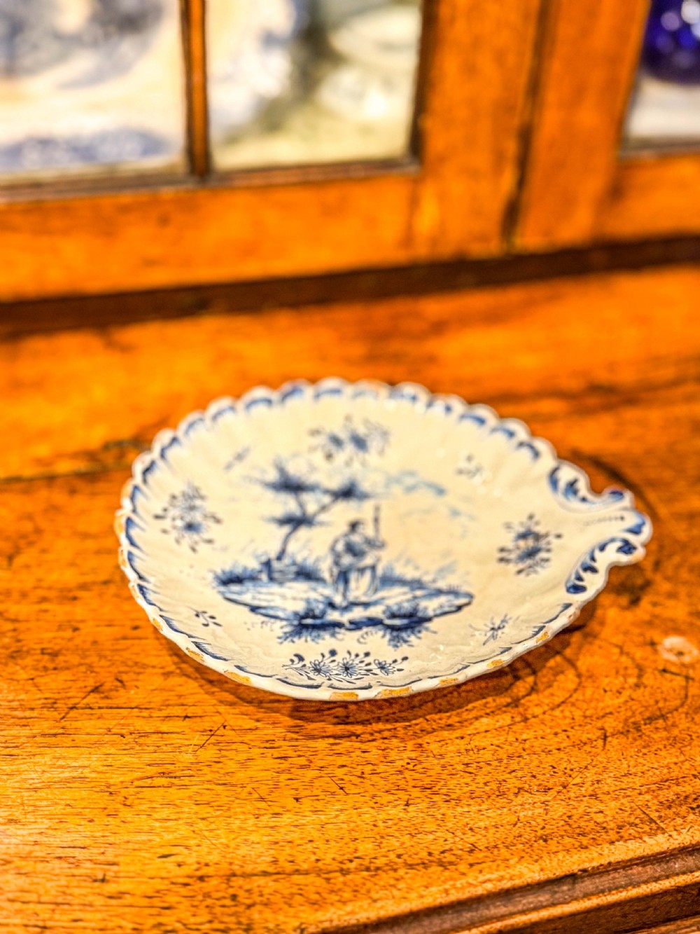 A nineteenth-century French blue and white faience shell-shaped vide-poche dish decorated with a central figure, floral sprigs, and a scalloped rim. View III