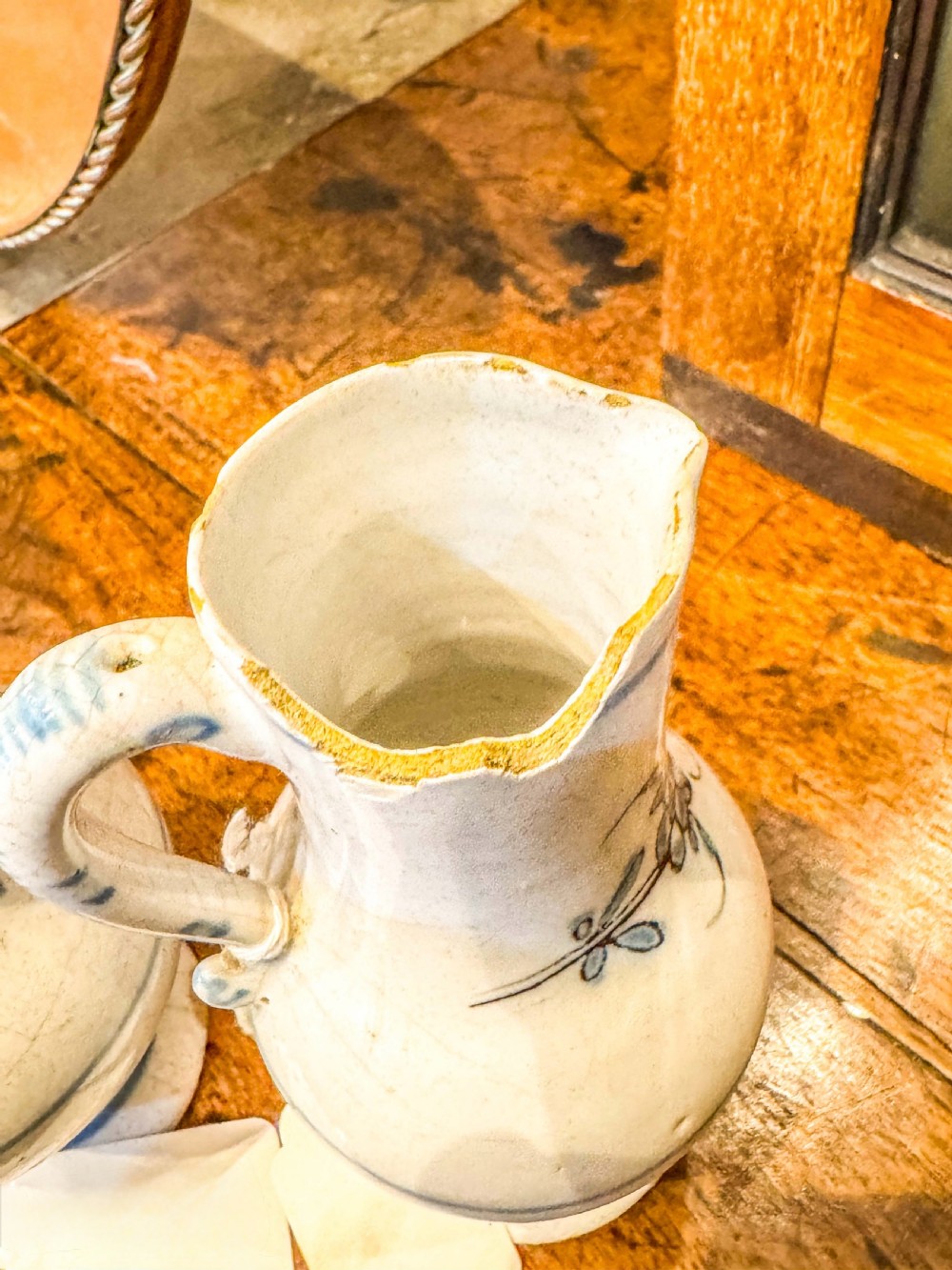 A pair of small antique off-white tin-glazed earthenware jugs decorated with hand-painted blue floral motifs on pedestal bases. View III