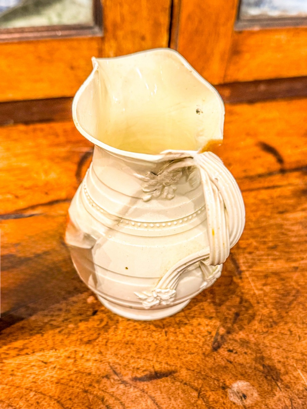 An 18th-century creamware pottery milk jug featuring moulded ribbed bands, a flared spout, and a looped handle. View II