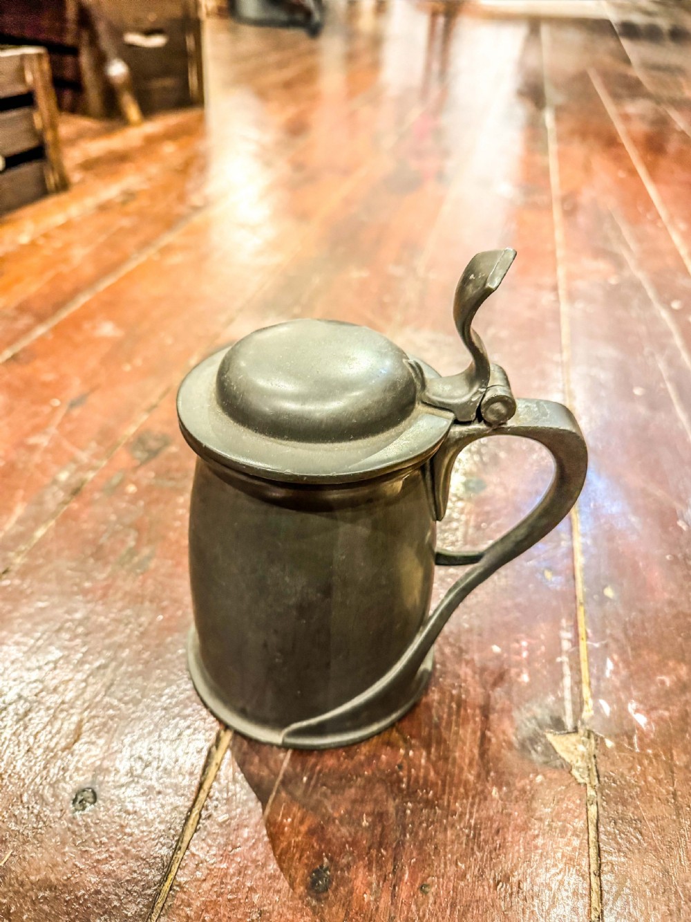 An antique lidded pewter tankard featuring a sinuous Art Nouveau handle and an oxidized dark grey finish.