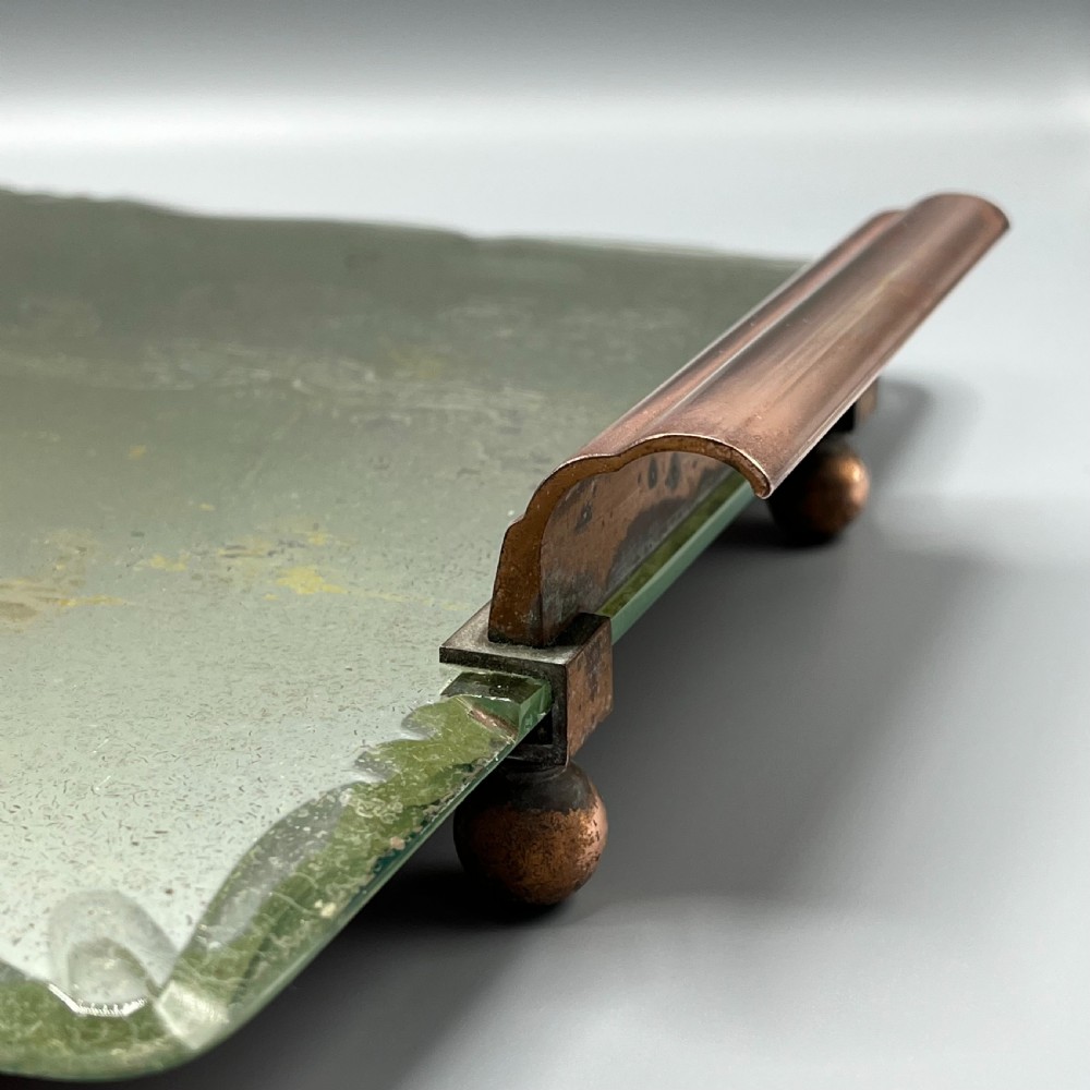A rectangular Art Deco mirrored glass tray featuring cut decorative edges and rolled copper handles supported by small footings. View V