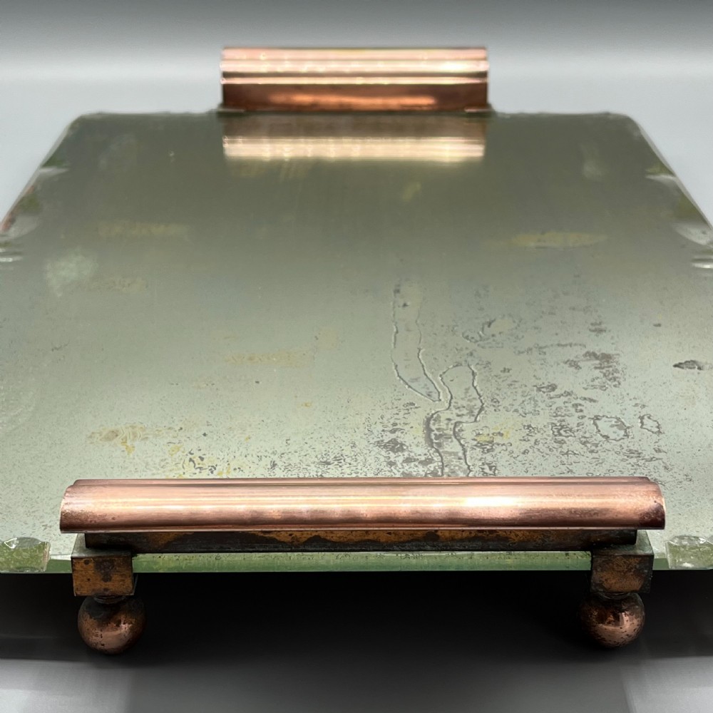 A rectangular Art Deco mirrored glass tray featuring cut decorative edges and rolled copper handles supported by small footings. View VI