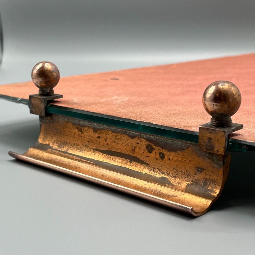A rectangular Art Deco mirrored glass tray featuring cut decorative edges and rolled copper handles supported by small footings. View XVII