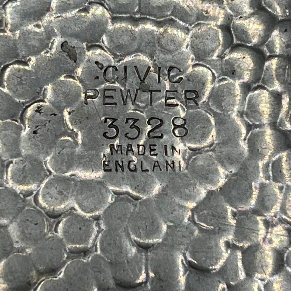 An oval hand-hammered pewter fruit basket featuring a high arching handle, geometric rim details, and small cast feet. View XII