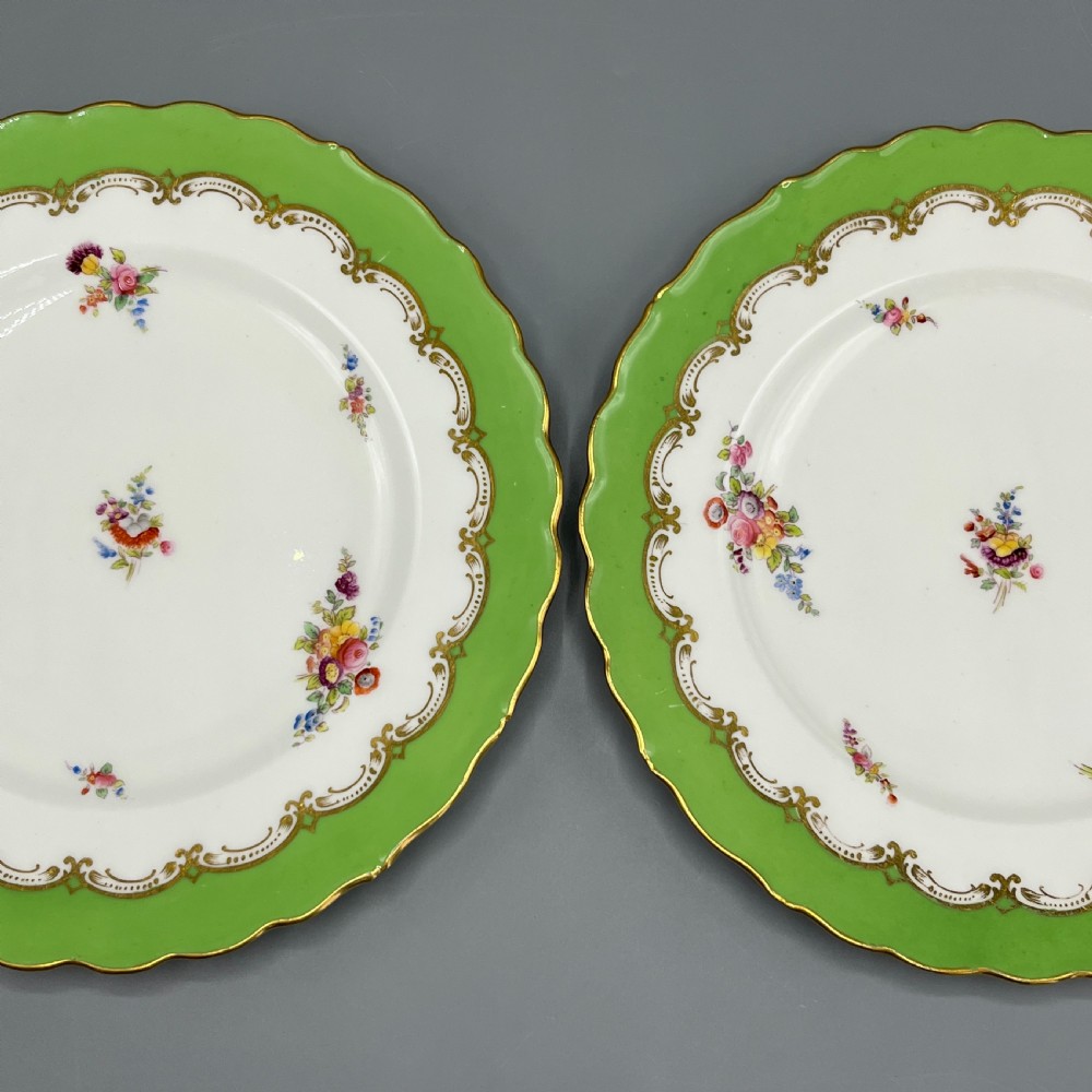 A pair of Victorian Coalport porcelain plates with bright green scalloped borders, gilded scrollwork, and hand-painted floral sprays on white centres. View II