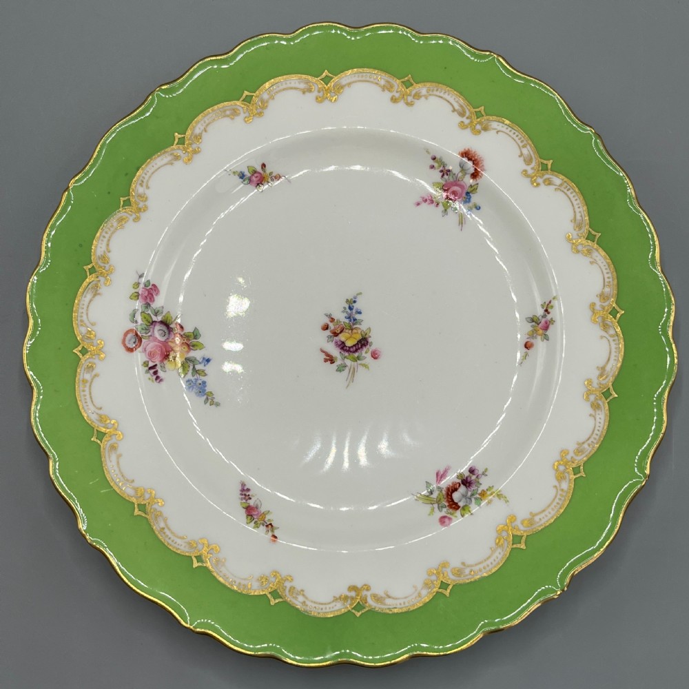 A pair of Victorian Coalport porcelain plates with bright green scalloped borders, gilded scrollwork, and hand-painted floral sprays on white centres. View IV