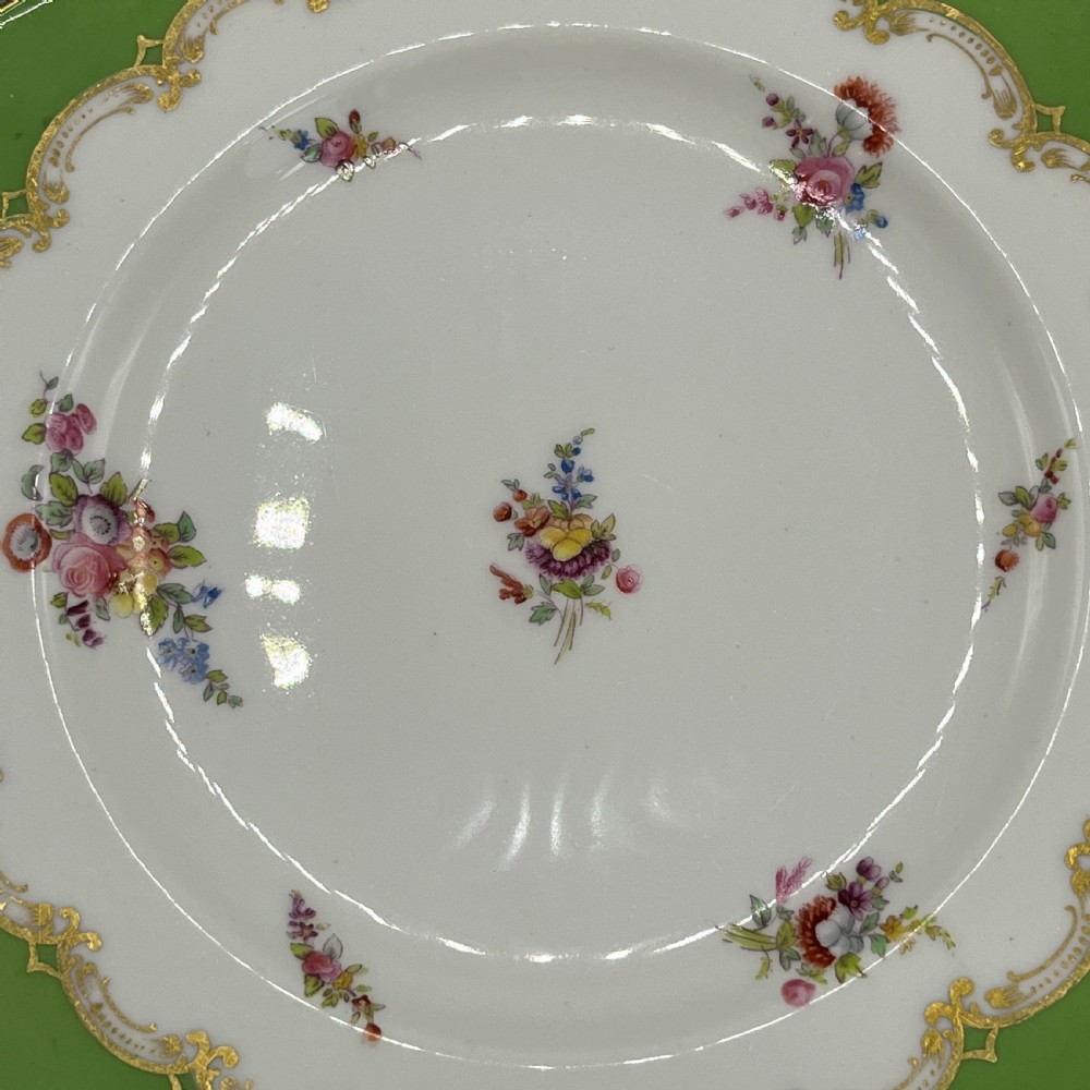 A pair of Victorian Coalport porcelain plates with bright green scalloped borders, gilded scrollwork, and hand-painted floral sprays on white centres. View V