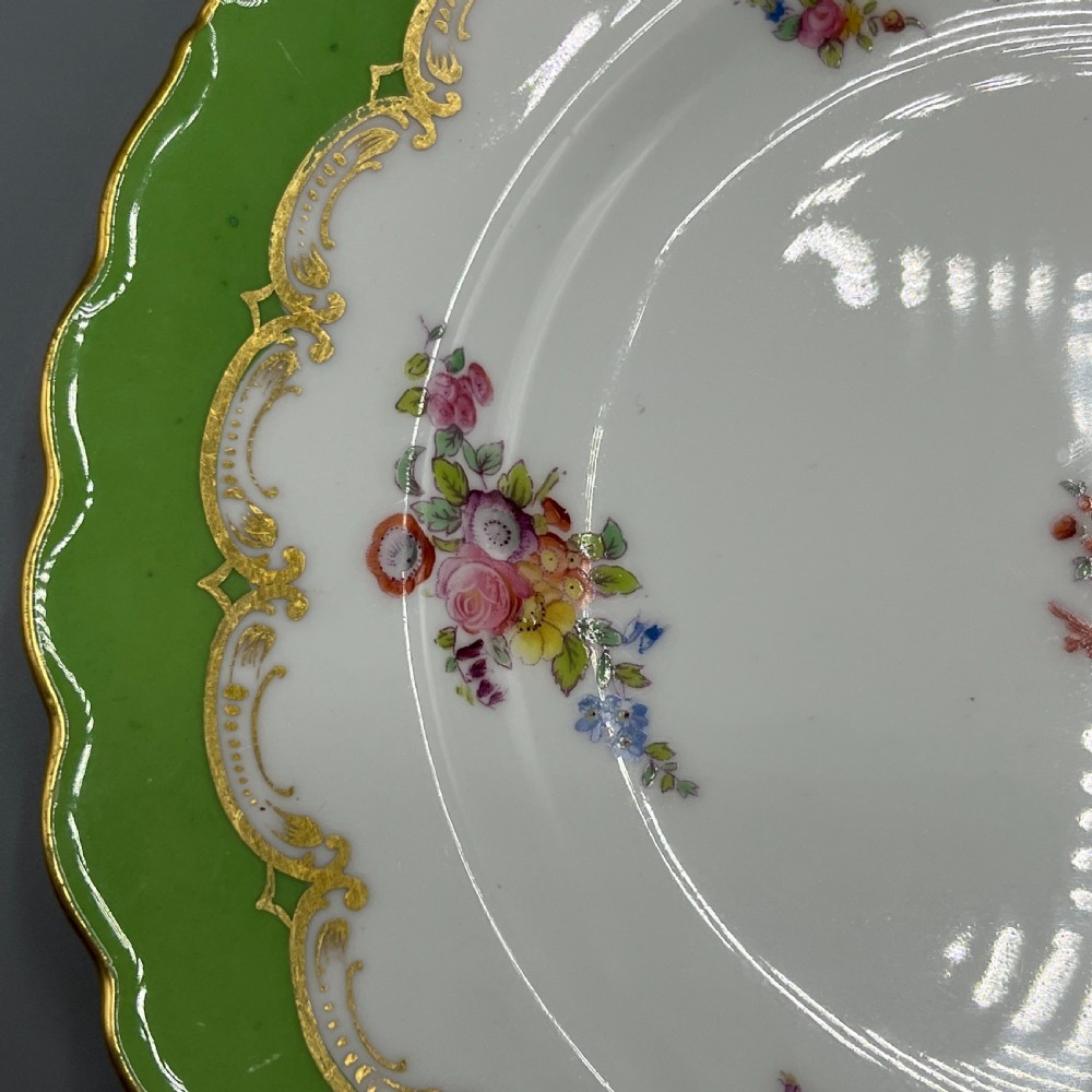 A pair of Victorian Coalport porcelain plates with bright green scalloped borders, gilded scrollwork, and hand-painted floral sprays on white centres. View VI